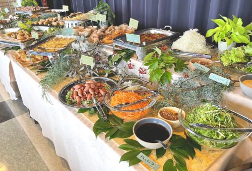 赤やオレンジの造花を飾るビュッフェ台 - 梅田経済新聞