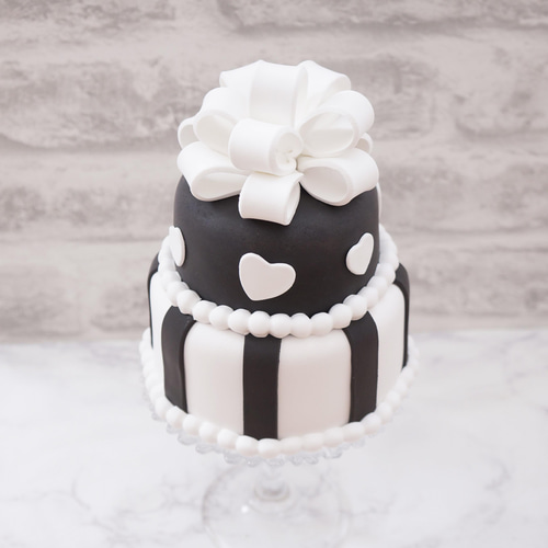 リボンケーキ🎀 フリルのように可愛く絞った生クリームと大きなリボンが特徴的なケーキ🎂 この大きなリボンはプラチョコというチョコでできていて、食べる事ができます🍫♡フルーツではなく絞りやプラチョコ細工を飾って仕上げるケーキは、いつもとは違う華やかさが