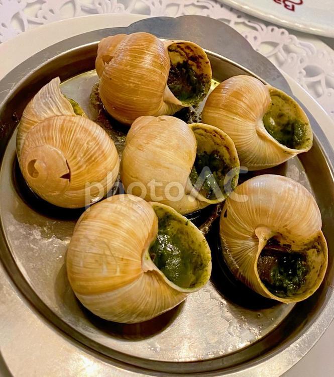 木製のテーブルの上の白い皿に様々 なソースで調理されたエスカルゴ カタツムリPremium写真